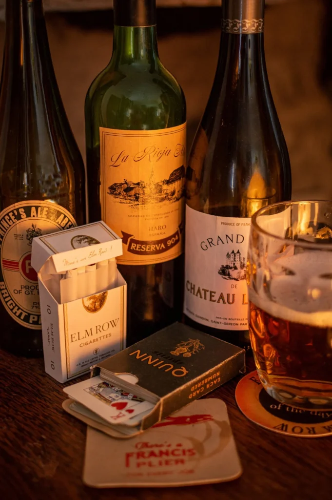 Period props: bottles, cigarettes, cards, and beer on a table
