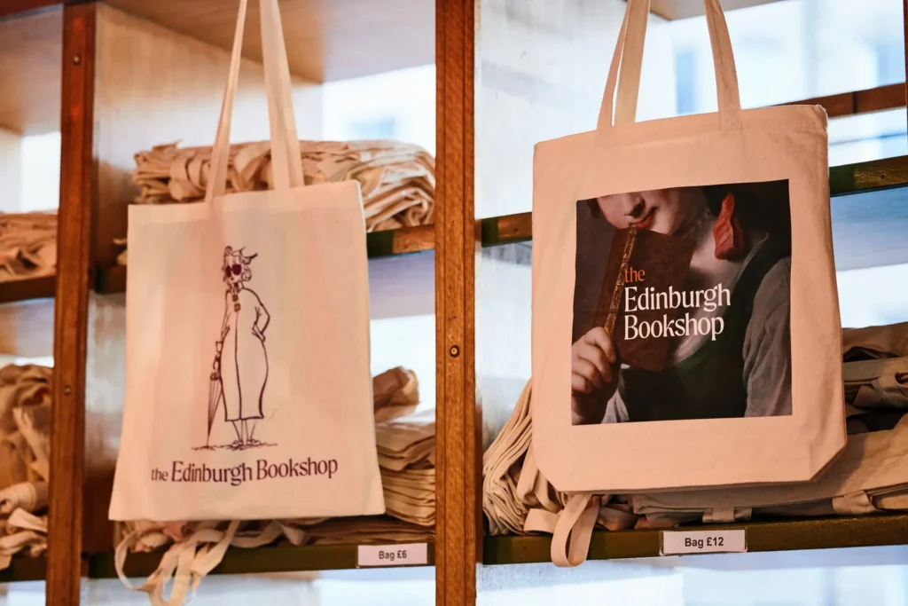 Two tote bags from The Edinburgh Bookshop, one with a sketch, one with a painting.