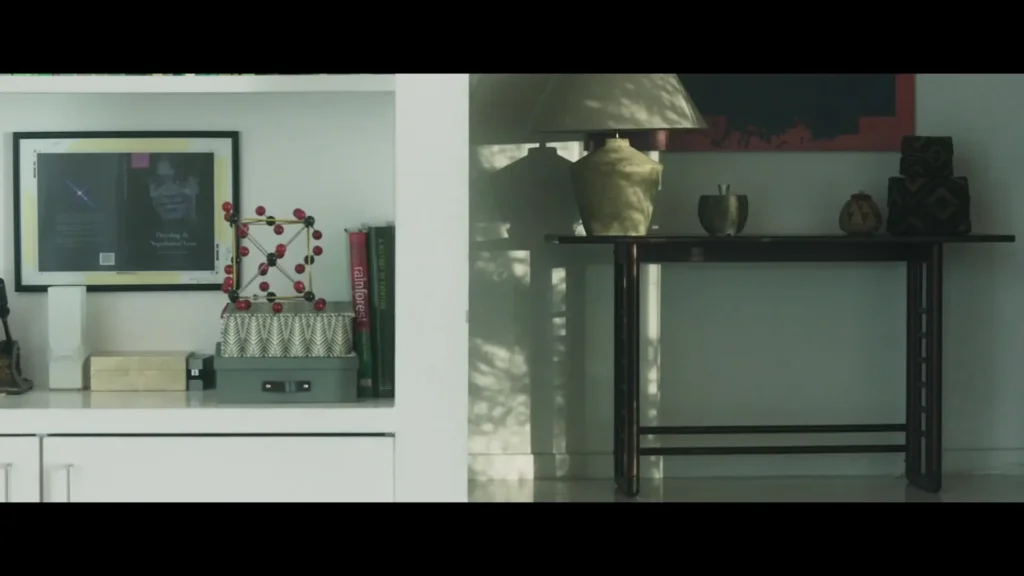 Bookcase with framed art, molecular model, and decorative items next to a console table.