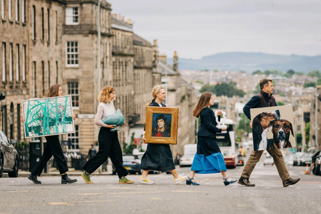 People carrying art across a street during New Town Art Month