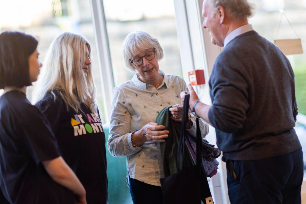 People at New Town Art Month event, one woman shows a scarf.