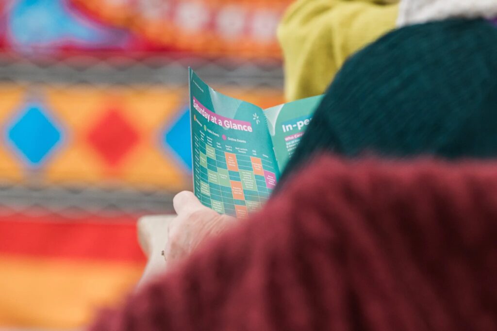 Person holding a "Saturday at a Glance" schedule at Push the Boat Out 2023