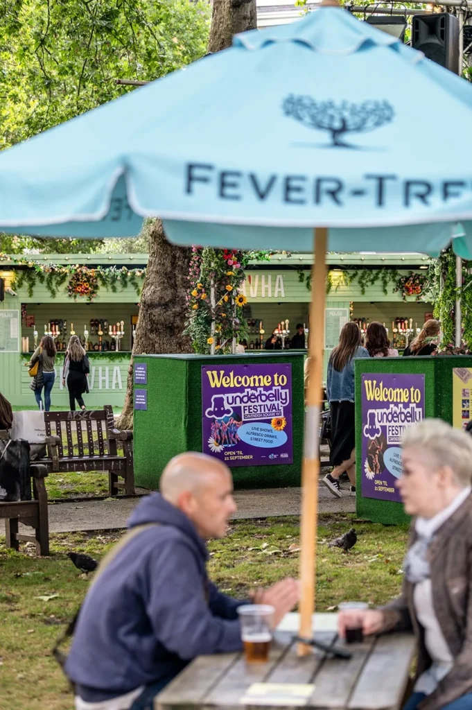 Underbelly Festival Cavendish Square: People relax under a blue umbrella at the outdoor festival.