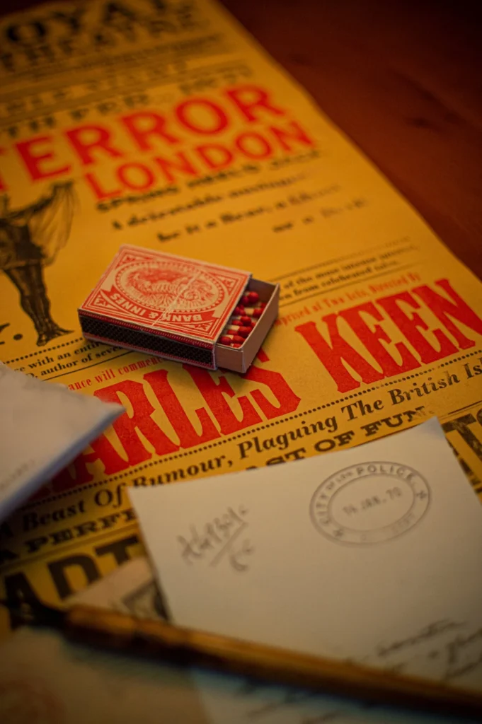 Period props: matchbox, letters, and "Terror London" poster