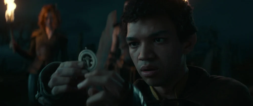 Young man examining a Dungeons & Dragons amulet with a torch-lit background