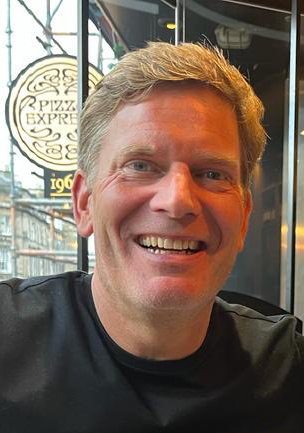Man smiling in front of Pizza Express sign