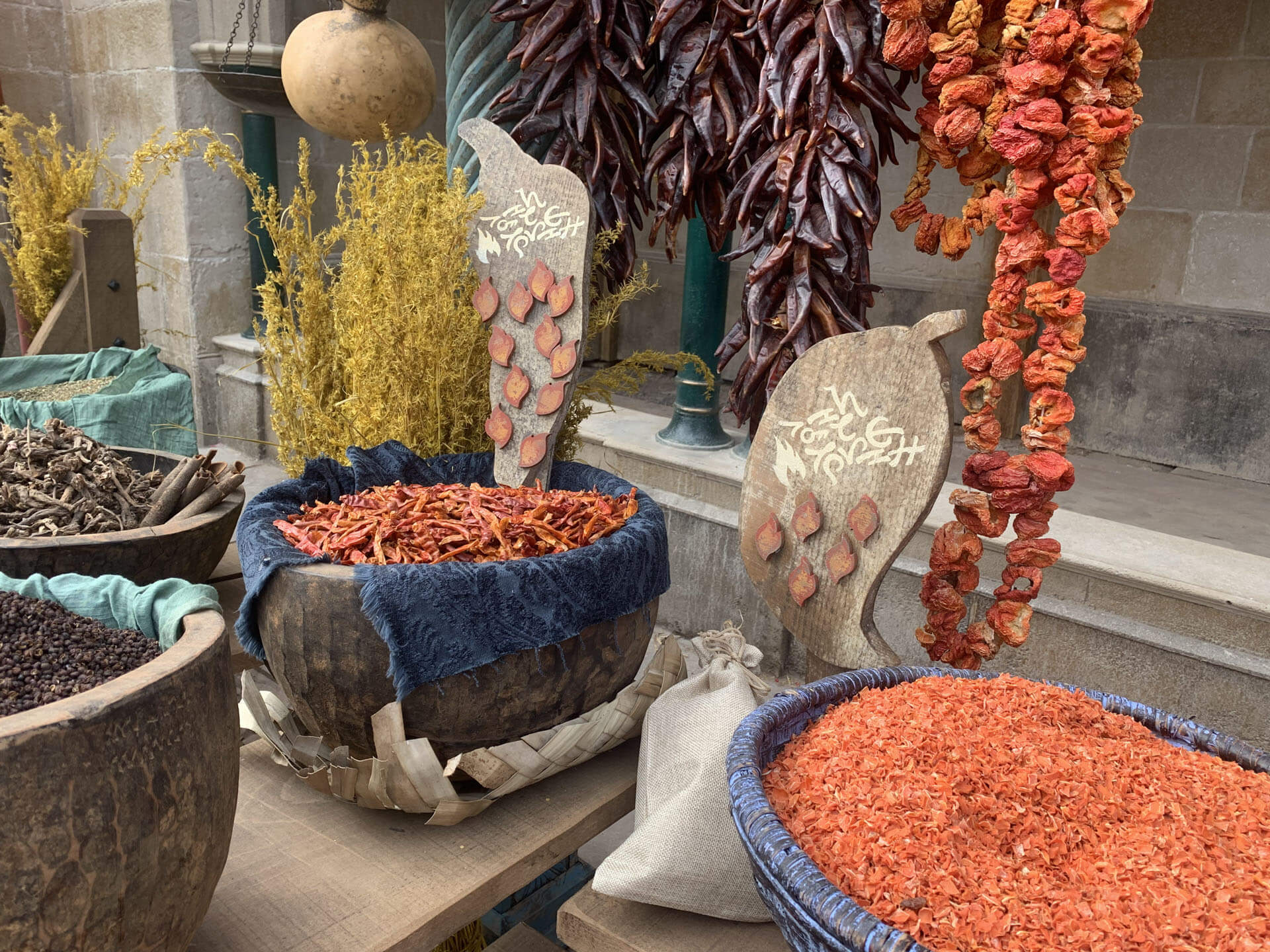 Baskets of dried chilies and spices at an outdoor market stall.