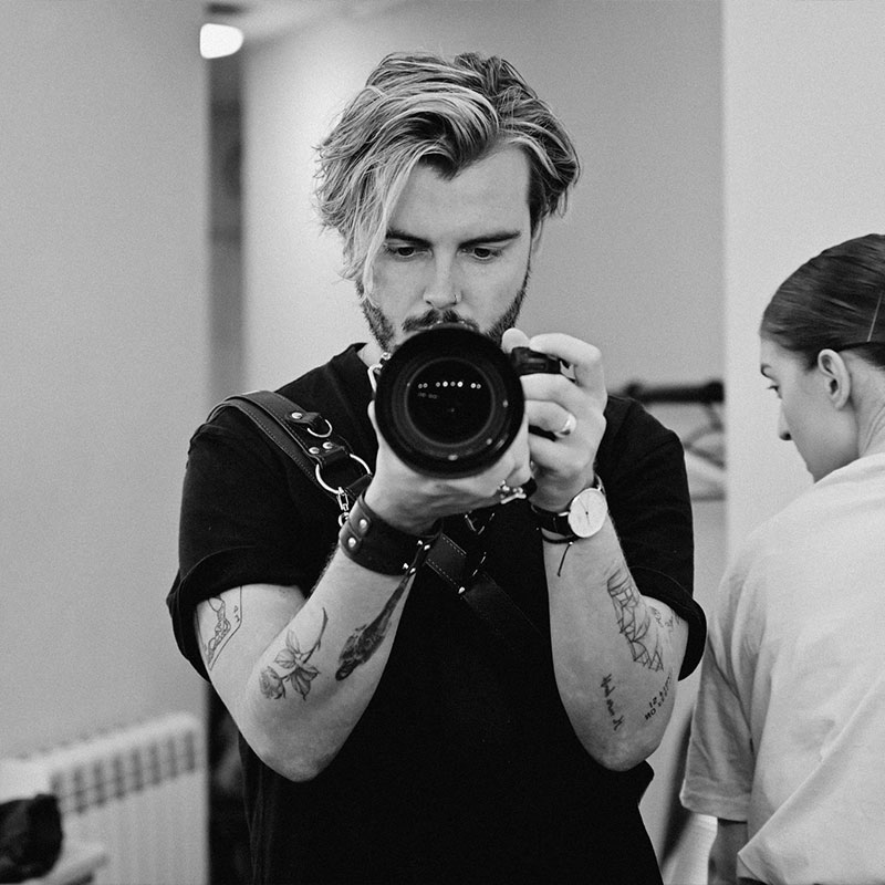 Photographer with camera, focusing on subject, black and white